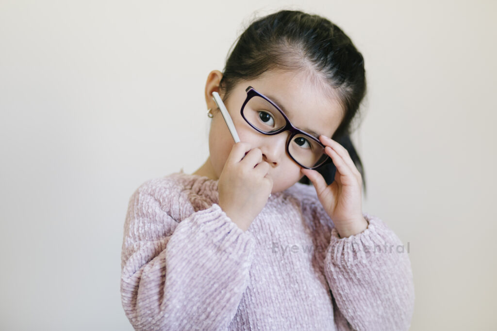 Child wearing a broken glasses. Her hand holding the frame arm that came off