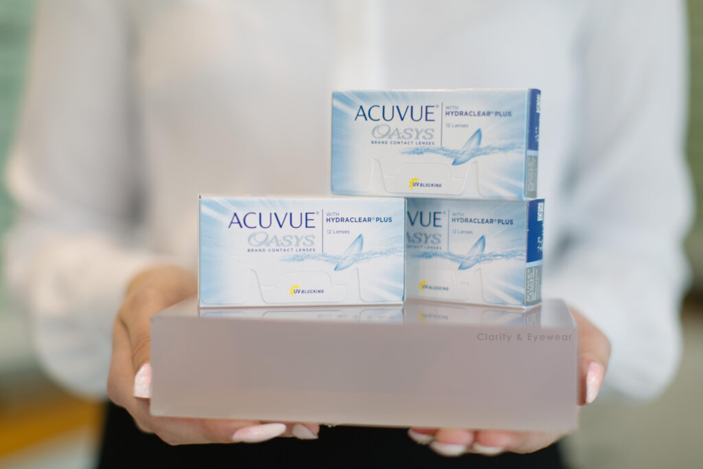 person holding 3 boxes of Acuvue Contact lenses