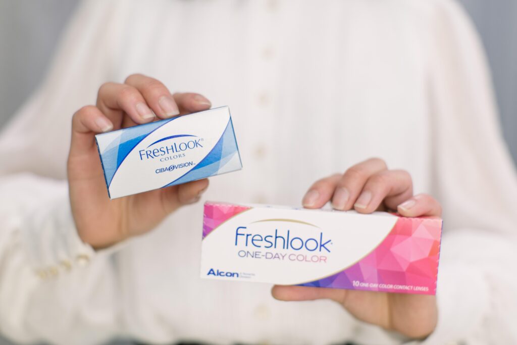 Each hand holding a box of Freshlook Coloured contact lenses