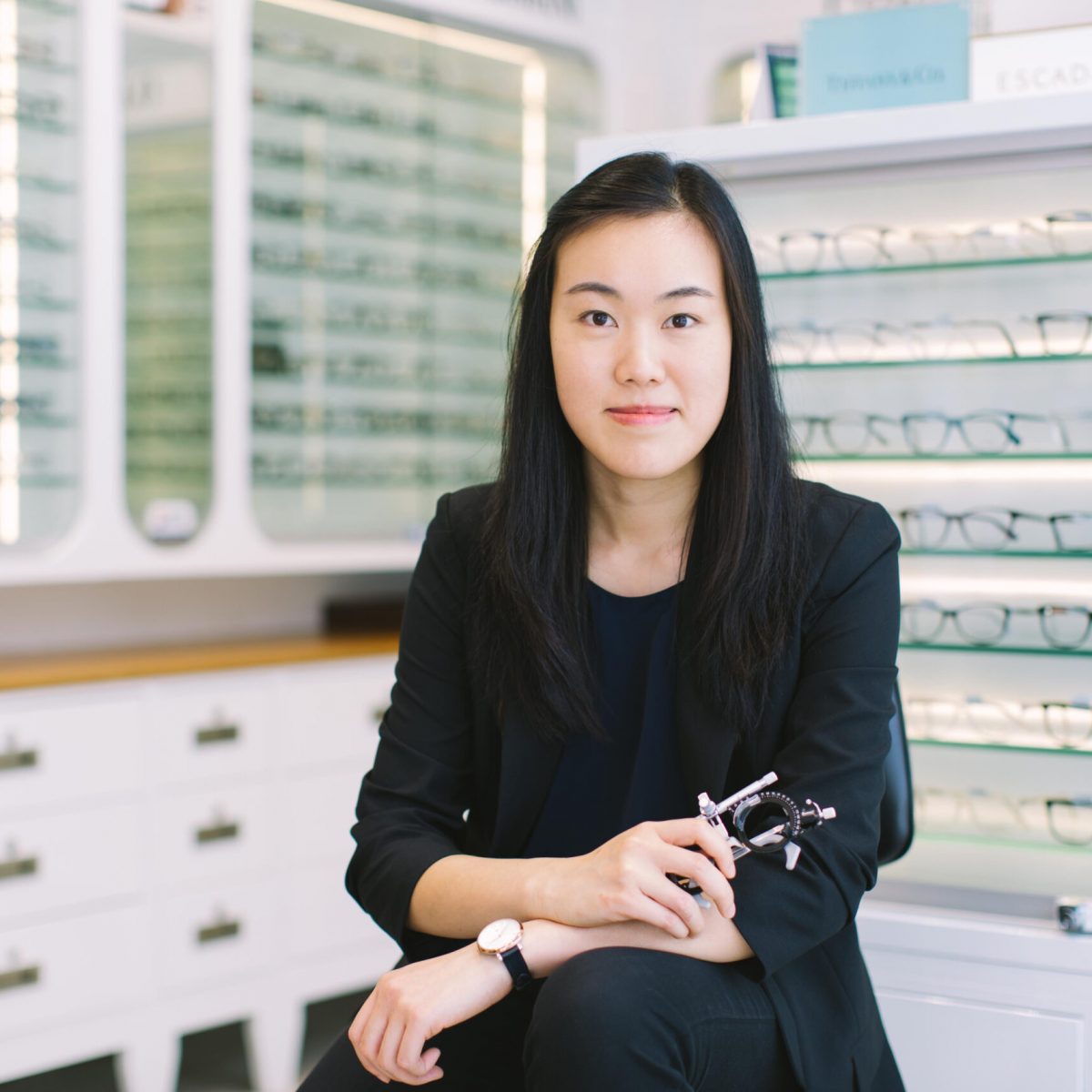 Dr. Sylvia Chau optometrist holding a trial frame